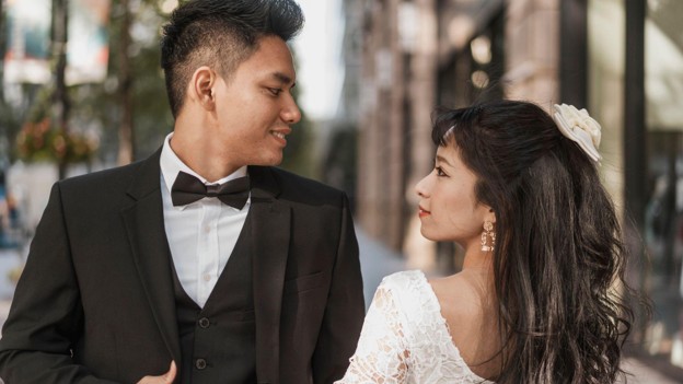 Ilustrasi pasangan muda mengenakan pakaian pernikahan yang saling menatap sebagai simbol persiapan pra-nikah. Artikel membahas tujuh checklist penting sebelum menikah, meliputi komunikasi, ekspektasi, pengelolaan konflik, keuangan, kesiapan mental, konseling pra-nikah, dan tes kesehatan sebagai fondasi membangun rumah tangga yang sehat.